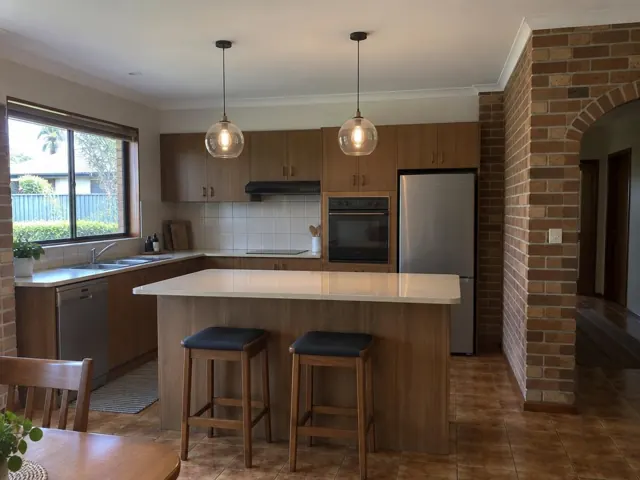 Kitchen with two glass pendant lights over an island, tiled floor and brick archway in Jewells